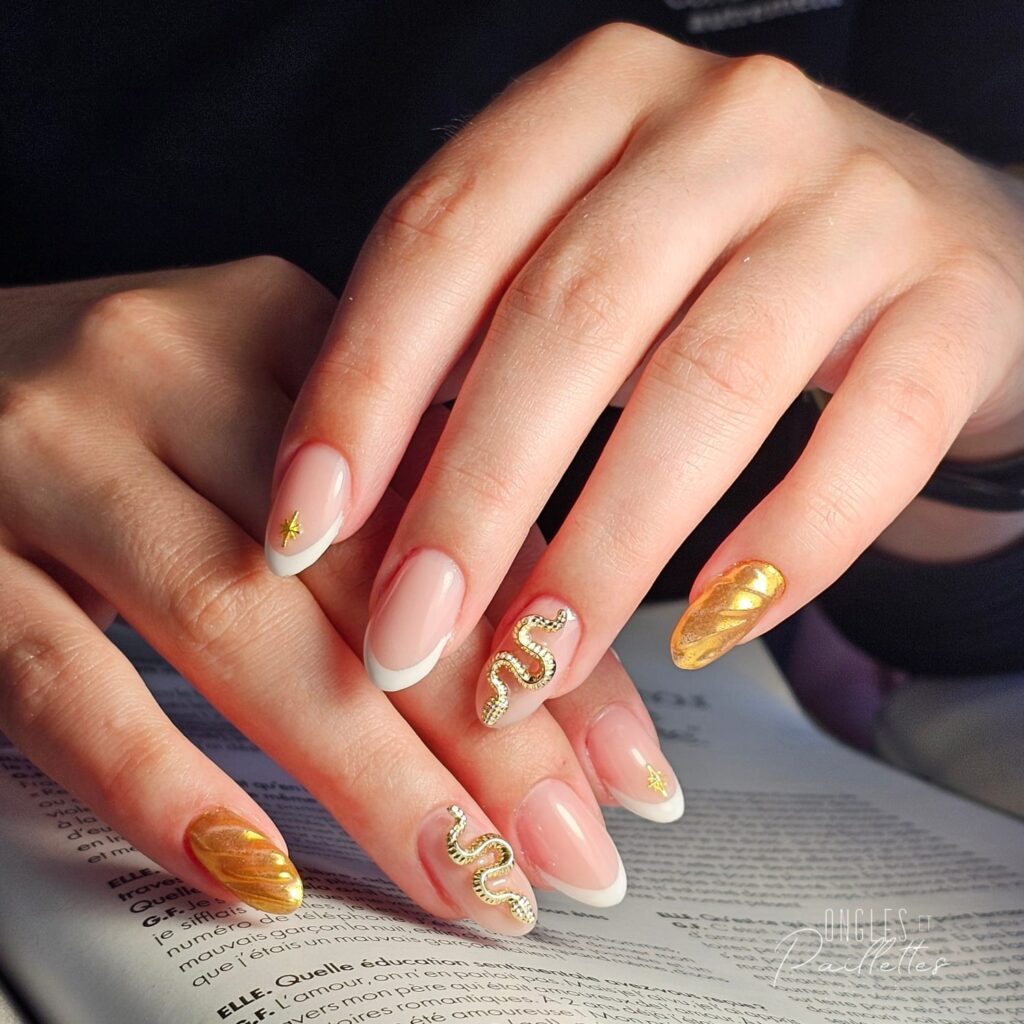 Ongles blancs et dorés. Un exemple de nail art avec des serpents sur les annulaires et une étoile sur les indexes.