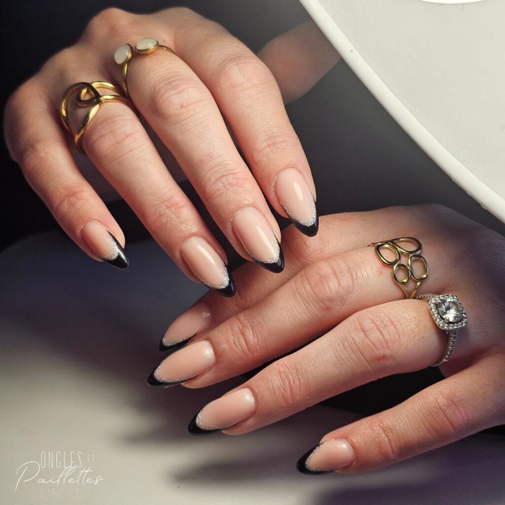 Ongles en forme d'amande, avec une pose de vernis semi-permanent rose nude, mais aux extrémités il y a de l'argenté et du noir.