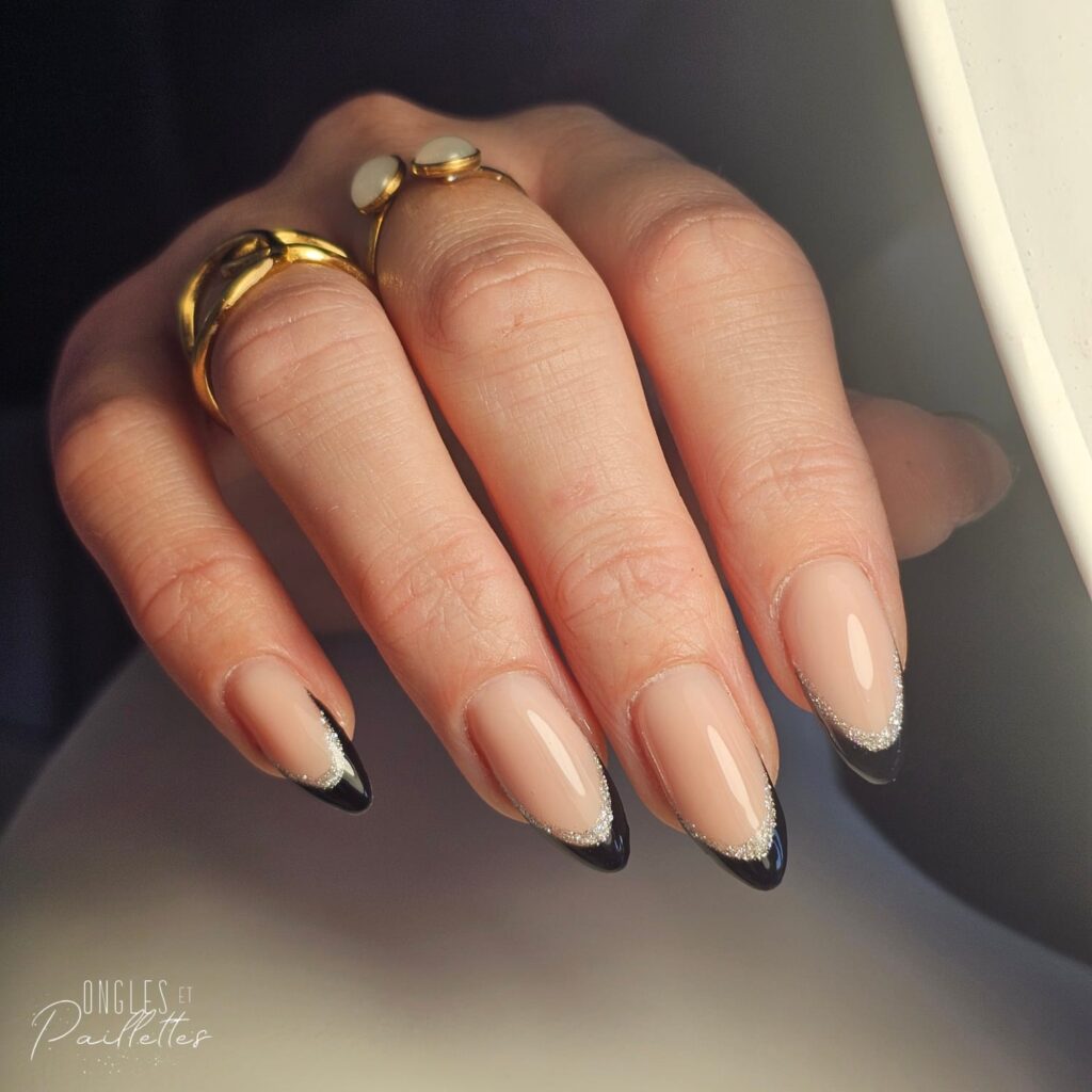 Ongles en forme d'amande, avec une pose de vernis semi-permanent rose nude, mais aux extrémités il y a de l'argenté et du noir.