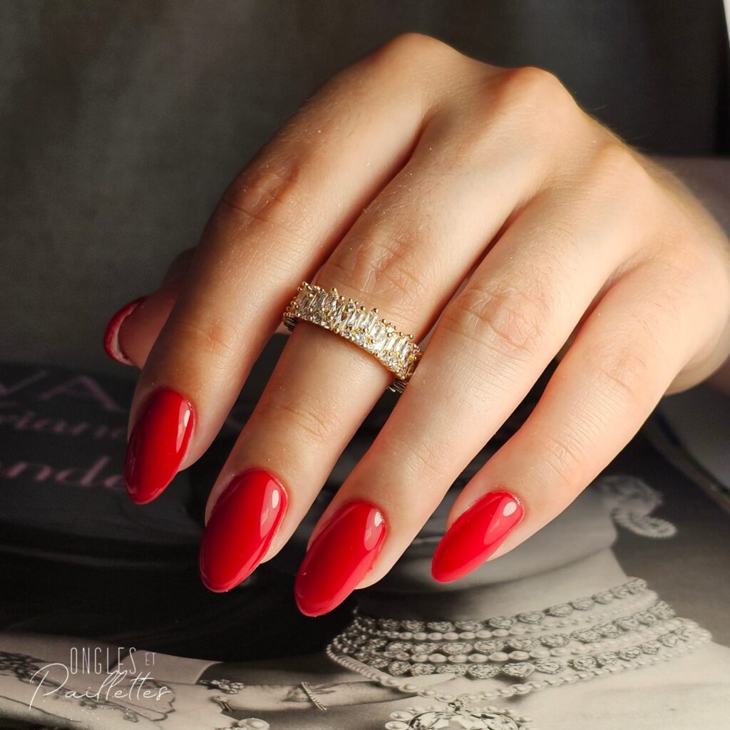Ongles en forme d'amande, avec une pose de vernis semi-permanent rouge pétant.